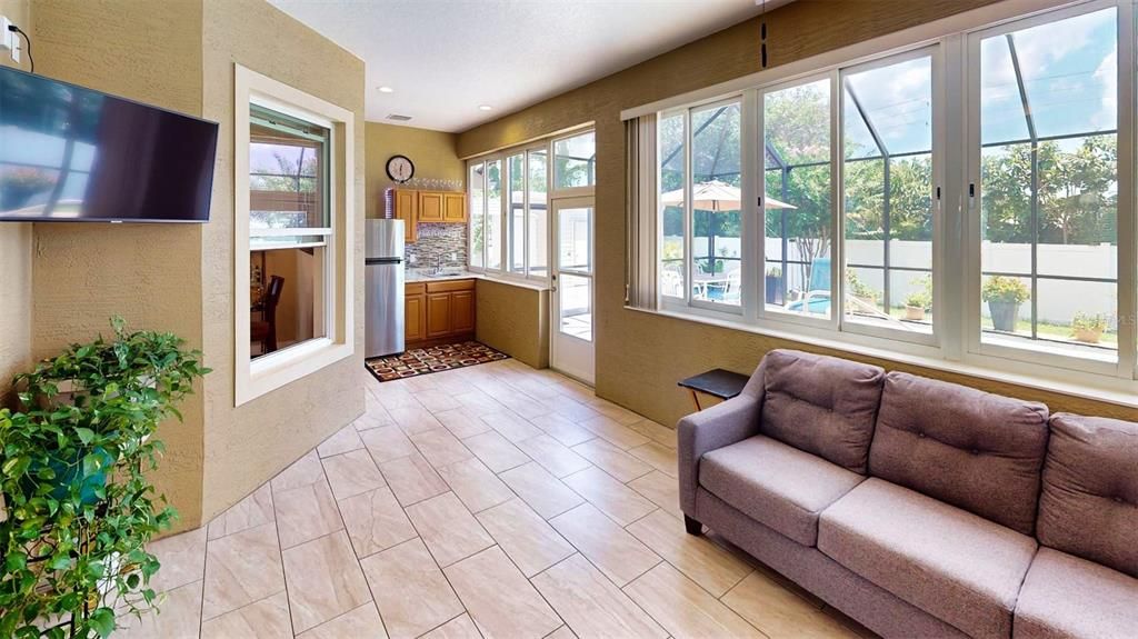 Florida room with double pane windows for energy efficiency, a ceiling fan for added comfort, a TV wall mount for easy entertainment setup, and a fully equipped summer kitchen, perfect for year-round enjoyment.