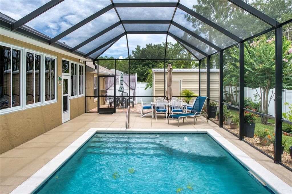 Solar-heated pool with a complete screen cage, featuring two large swim-outs and a bubbling water fountain for endless enjoyment.