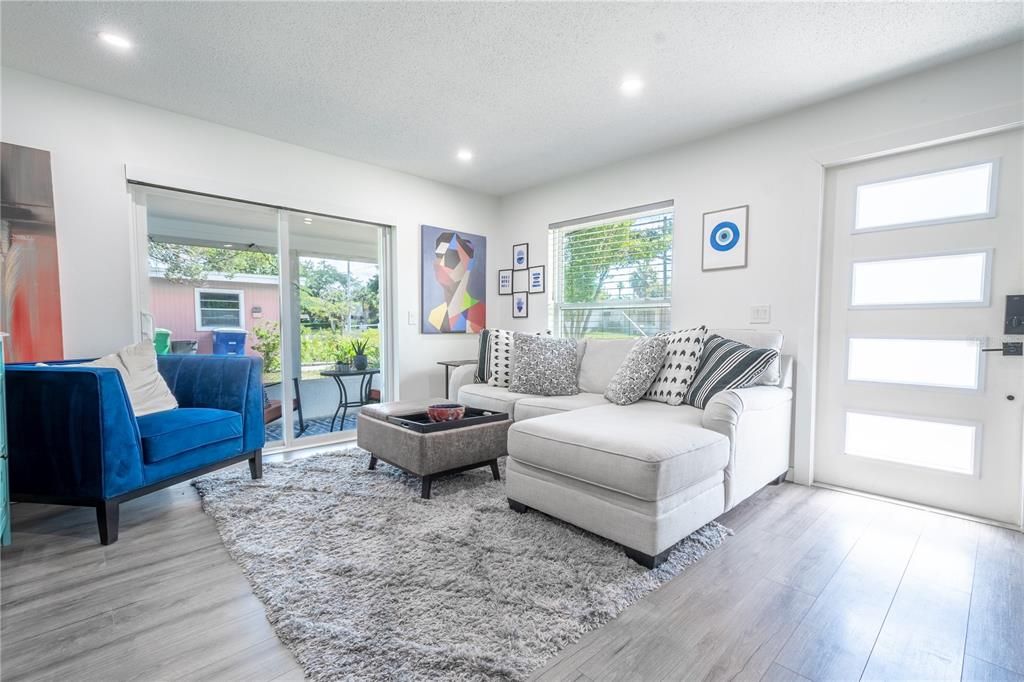 The living room features wood laminate flooring. The minimalistic style front door with frosted glass inserts blends luxuriously with the interior.