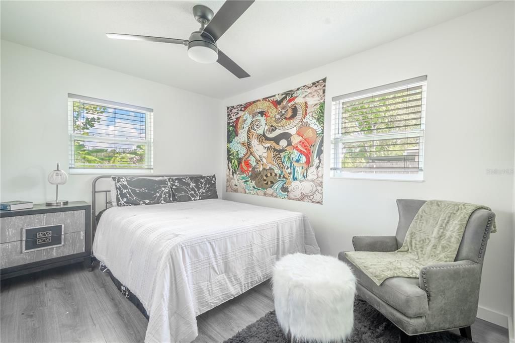 Bedroom 3 features a neutral color palette, ceiling fan, wood laminate flooring and a built-in closet.