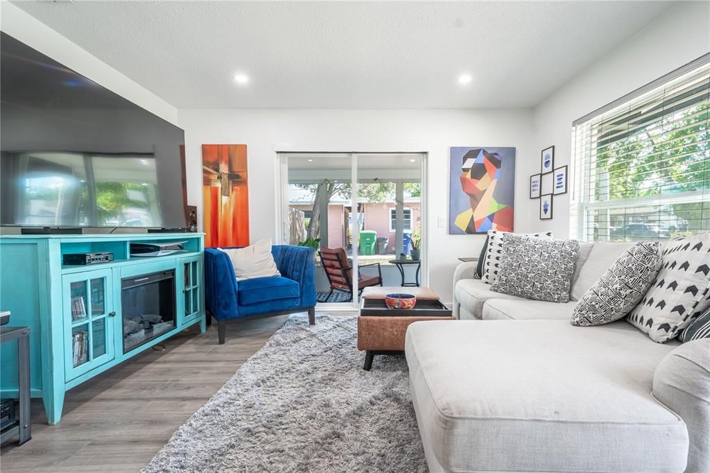 The living room features a picture window, wood laminate flooring, and sliding glass doors to a screened in porch.