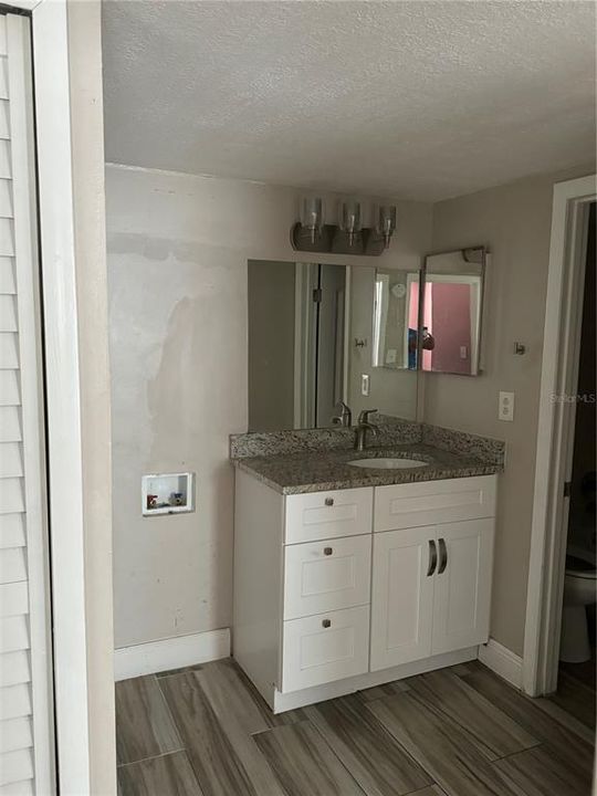 Bathroom Vanity next to Washer and Dryer Hookup. All Tile