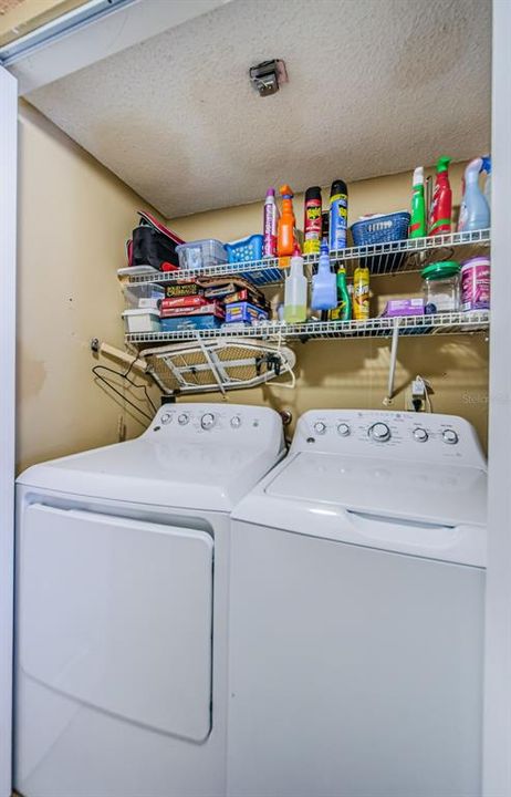 Washer and Dryer with storage shelving is located in the hallway behind bifold doors