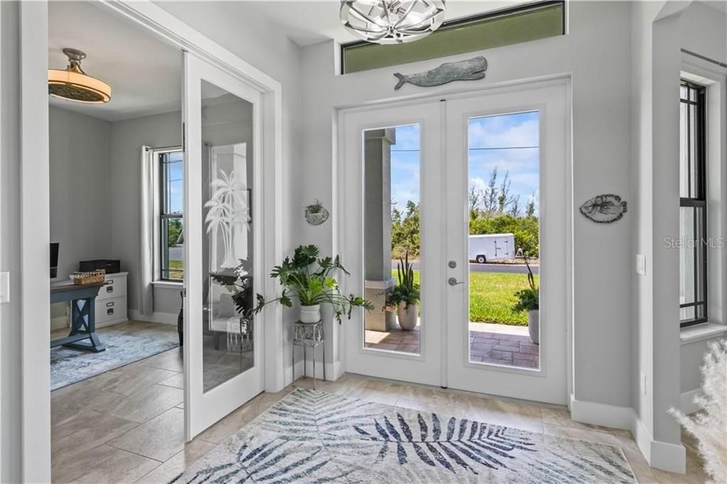 Foyer entrance with plenty of natural light, french doors, and light tile flooring - welcomes you into the flexible floor plan!