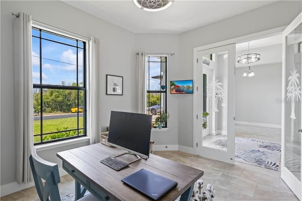 Office space off of the foyer featuring light tile flooring and a chandelier