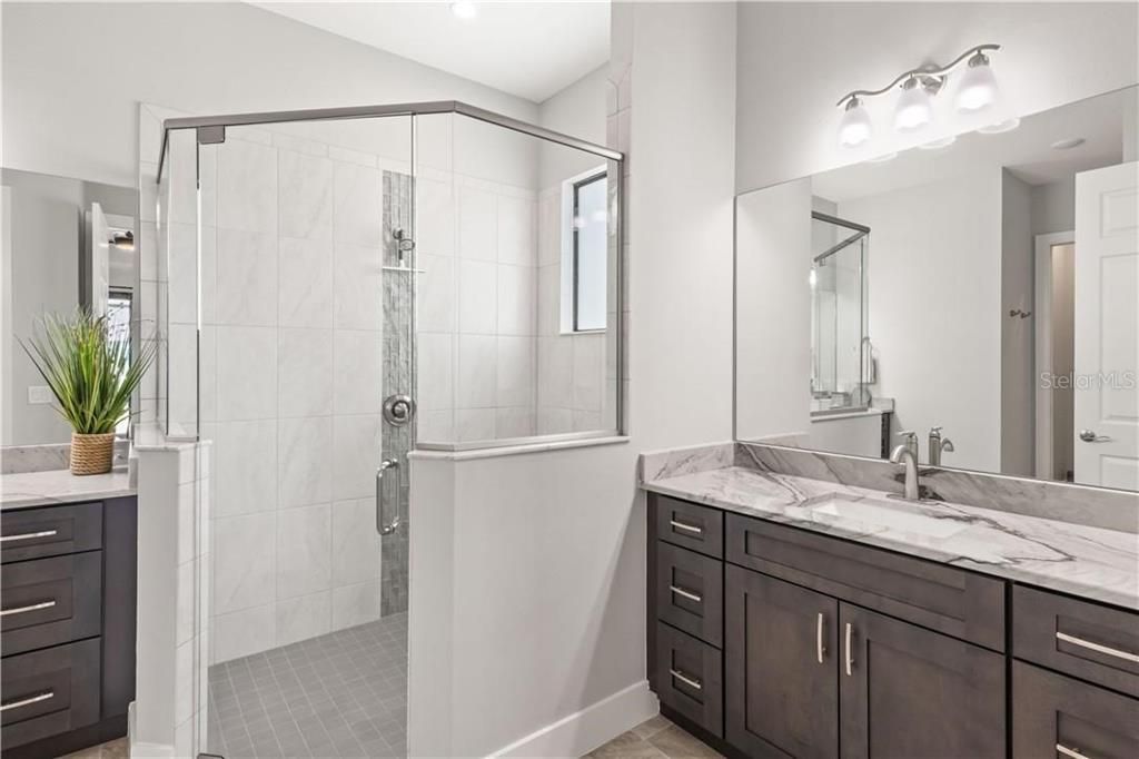 Close up of the walk in shower with custom tile accents, the beautiful granite on the vanities and the large mirrors!