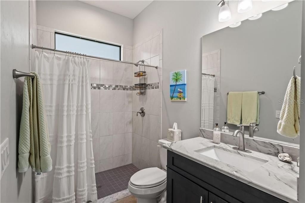 Pool bath for easy access outside!  Features walk in shower, vanity, and another transom window to allow the natural light in!