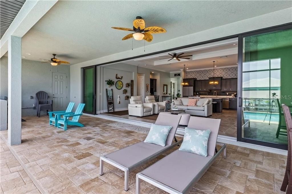 View of patio featuring outdoor lounge area and multiple ceiling fans!  Slider doors are hurricane impact and disappear for that wide open extension of living areas!  With access to the pool bath and pre-plumbed for an outdoor kitchen!