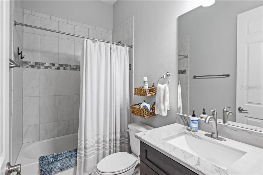 Guest bathroom featuring vanity, toilet, and shower/tub combo - like everything else in the home, no detail left out - even the tile accents were well chosen!