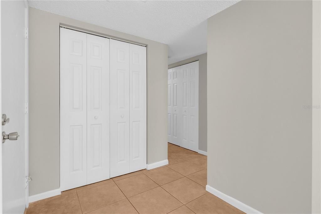 foyer with coat/storage closet and view of laundry closet with stackables