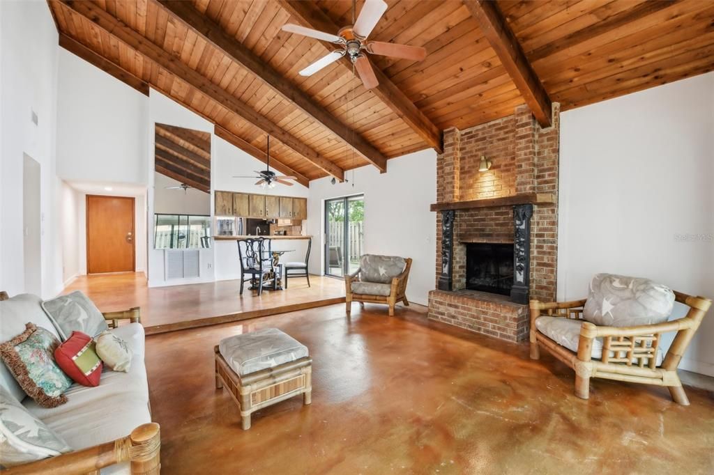 The dining area flows naturally into the spacious living room with a floor to ceiling brick fireplace centering the space and TRIPLE SLIDING GLASS DOORS that open up to the rear lanai for indoor/outdoor living at its finest.