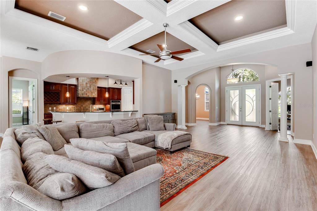 Large family room with tray ceilings and built in entertainment center. Views of the pool and lush backyard landscaping. Open to the kitchen.