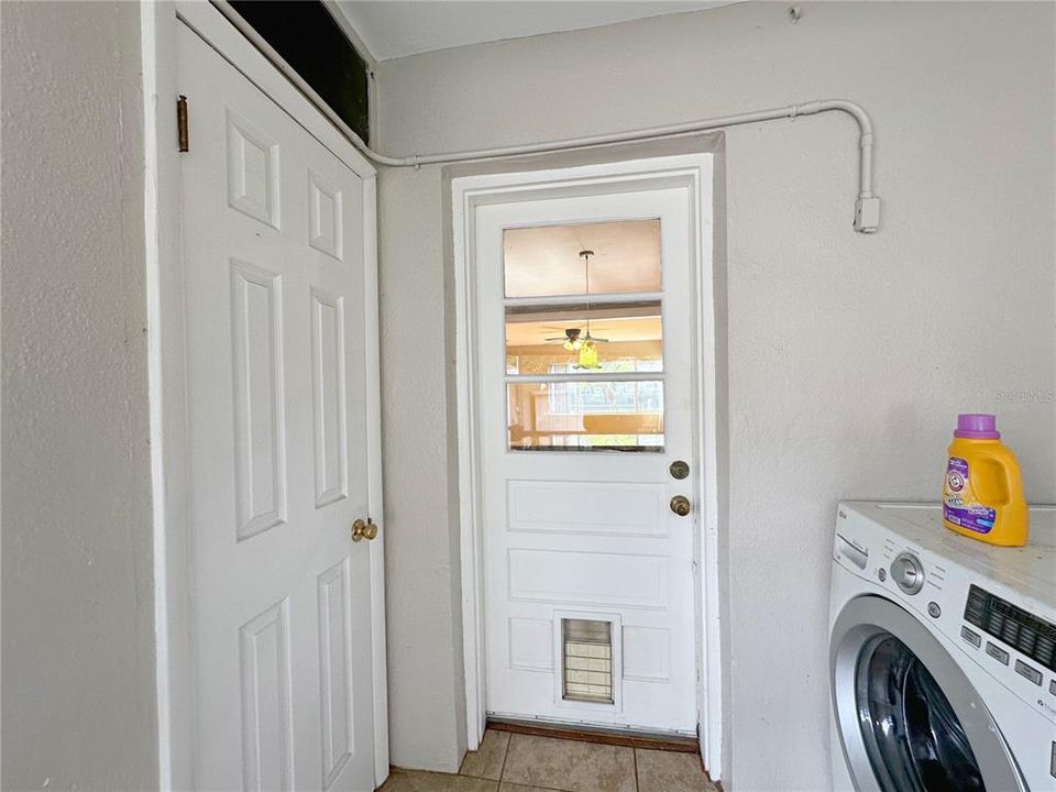 View of rear entrance to main home with door to half bath on the right and washer and dryer on the left.