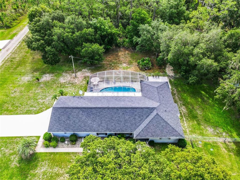 Aerial view of the home shows lots of mature trees on the 1 acre lot.