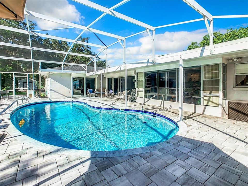 Backyard pool with pavers and screened lanai.