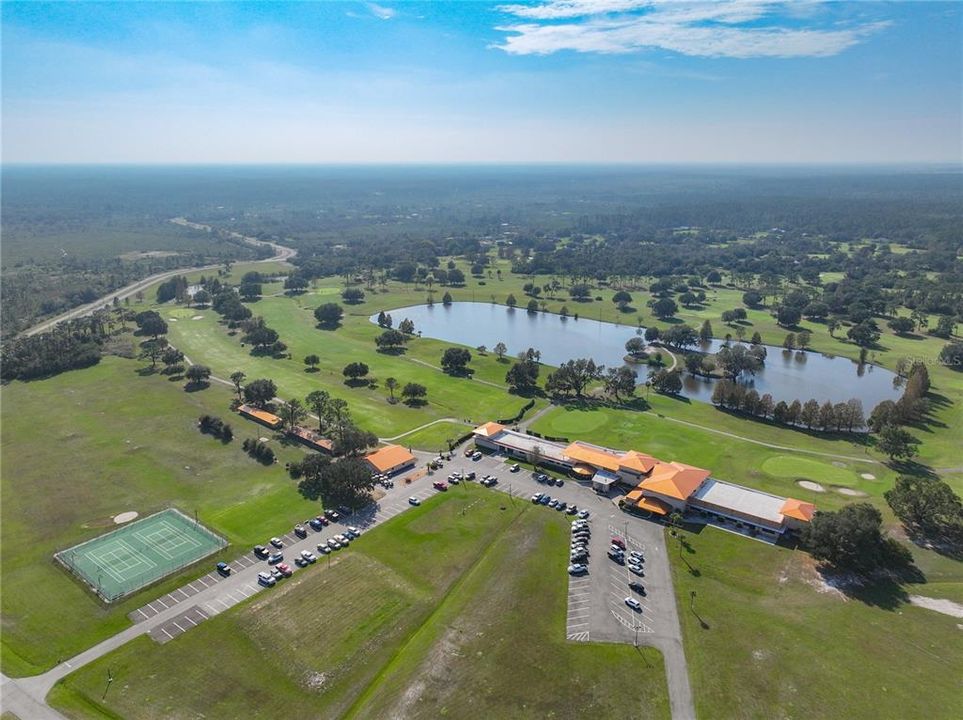 Aerial view of the clubhouse, golf course, tennis courts, and parking lot.