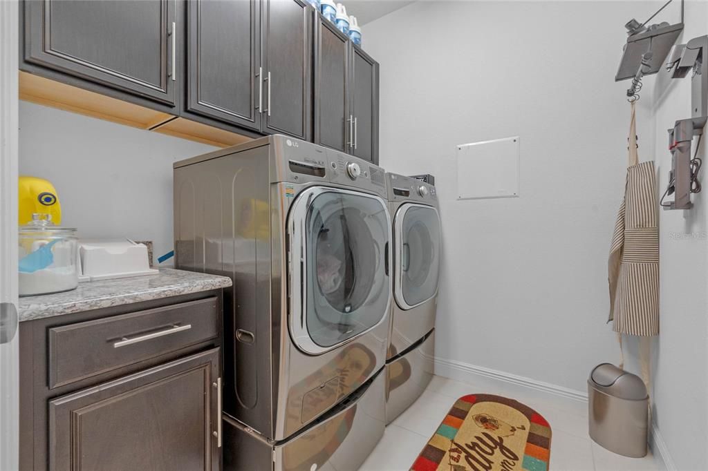 The laundry room is equipped with newer washer and dryer units, complemented by wood cabinetry for ample storage and a convenient laundry sink for added functionality.