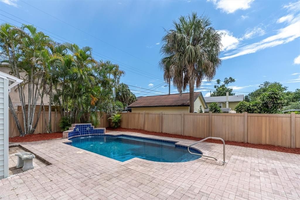 Paved Patio Surrounding a Newly Resurfaced Pool With Fountain Feature