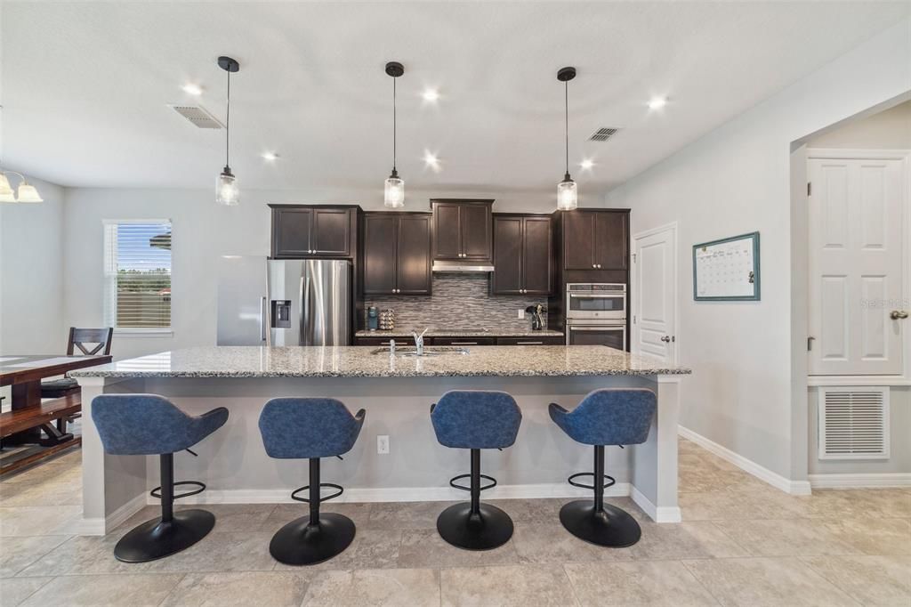 The home chef will delight in the beautiful kitchen featuring upgraded STAINLESS STEEL APPLIANCES, rich cabinetry with complimentary GRANITE COUNTERS and backsplash, CUSTOM BEVERAGE BAR complete with a beverage fridge and there is casual dining at the expansive ISLAND under pendant lighting.