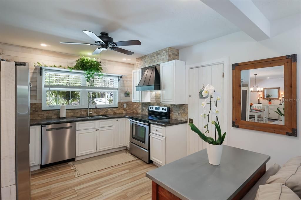 Coastal-style cabinetry, granite countertops, with a custom stone backsplash and stainless steel appliances makes this kitchen warm and inviting.