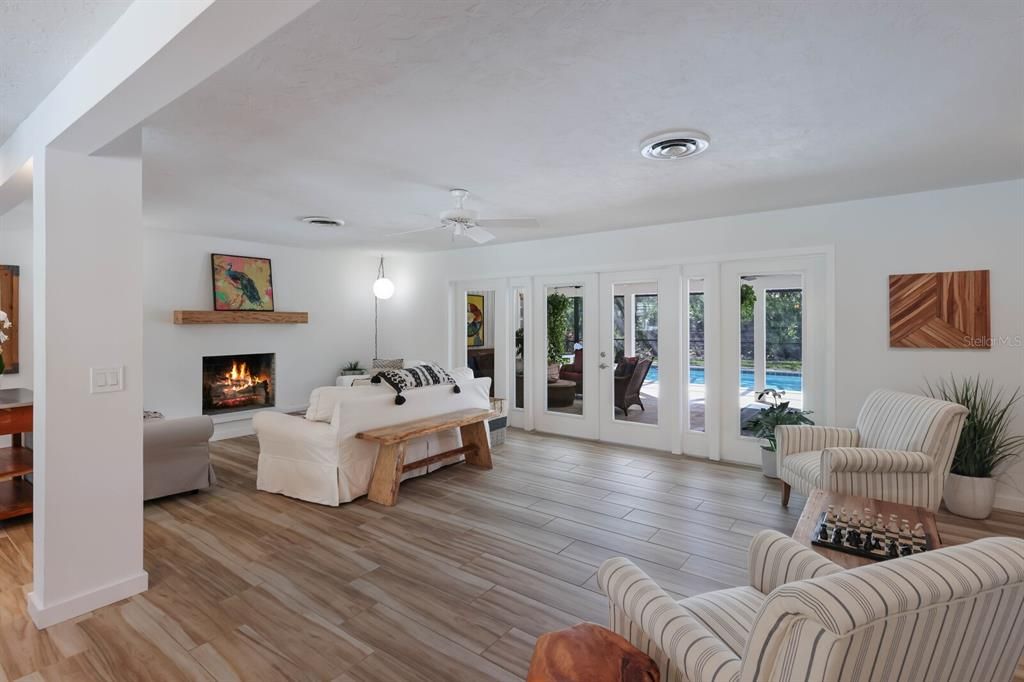 Adorned with a sleek, wood burning fireplace, the living room features beautiful French doors and windows which allows an abundance of light into the home and a beautiful view of the screened lanai and pool.