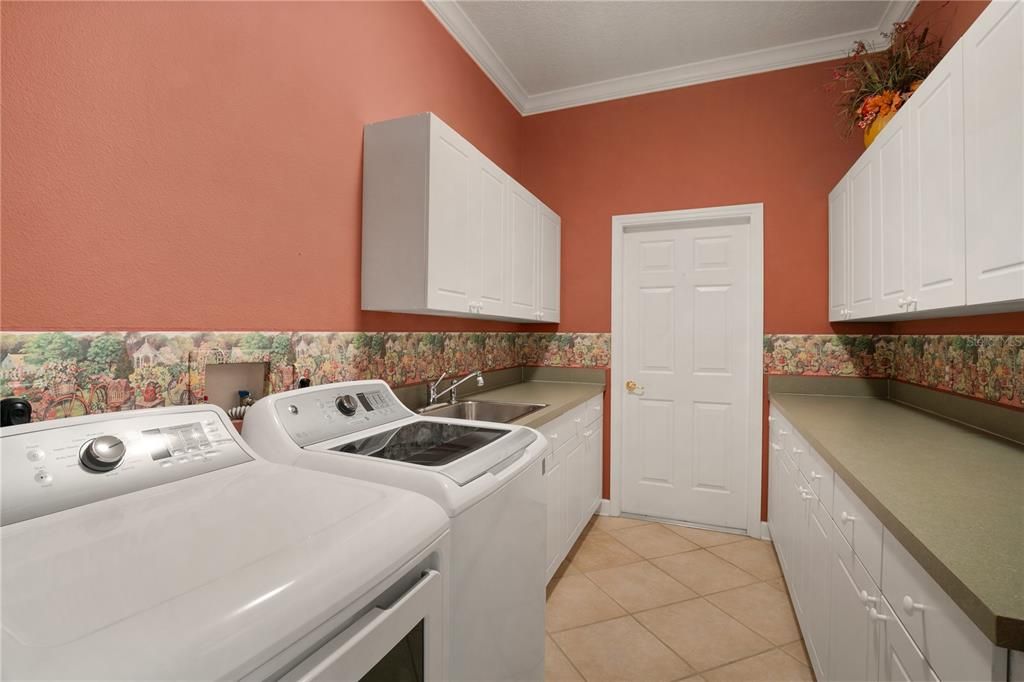 The laundry room offers lots of storage, counters space & cabinets.