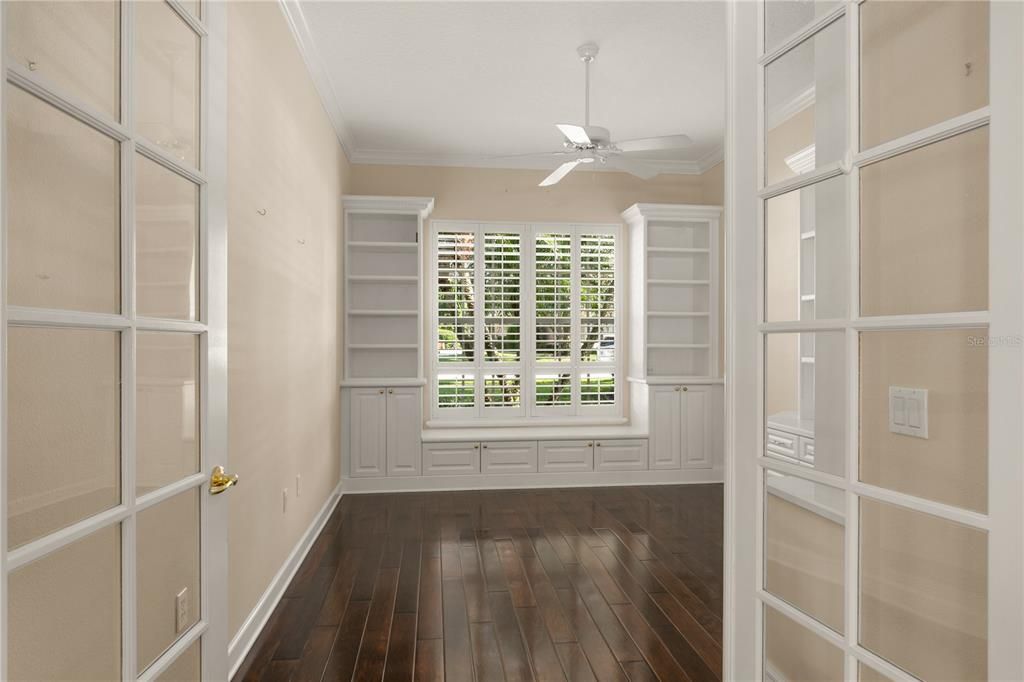 A large office/den has built-in storage and a window seat.