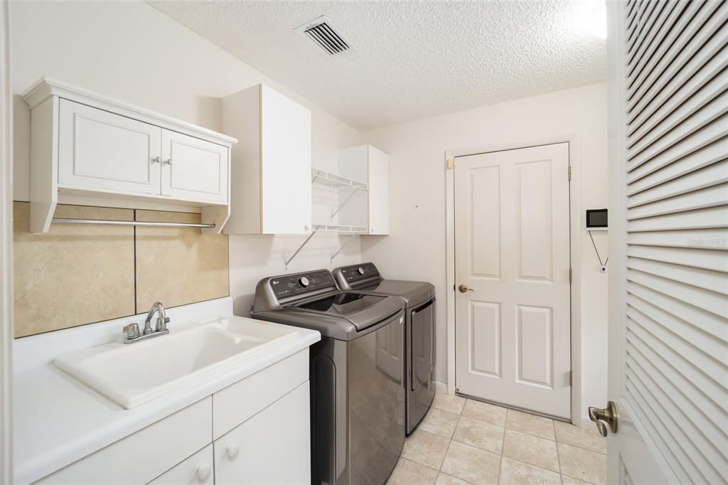 Newer washer and dryer along with storage and a deep sink.