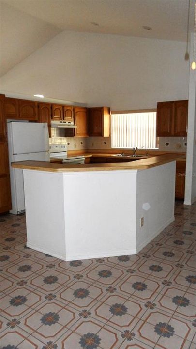 Kitchen with Vaulted ceiling, recessed lighting and oak cabinetry.