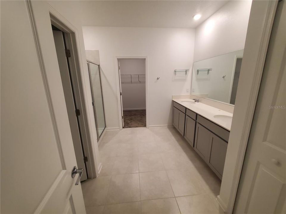 Master bath with double vanity on the right and shower on the left.  In the background is the huge Walkin closet.