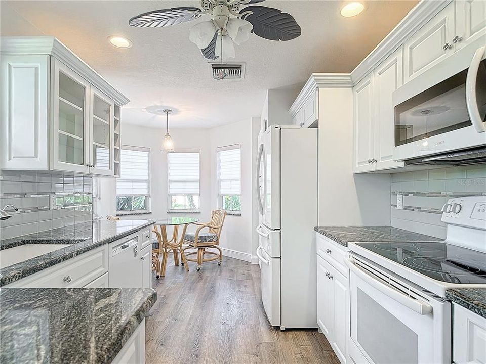 This kitchen features Custom cabinets, Granite countertops, Luxury wood floors, and more.