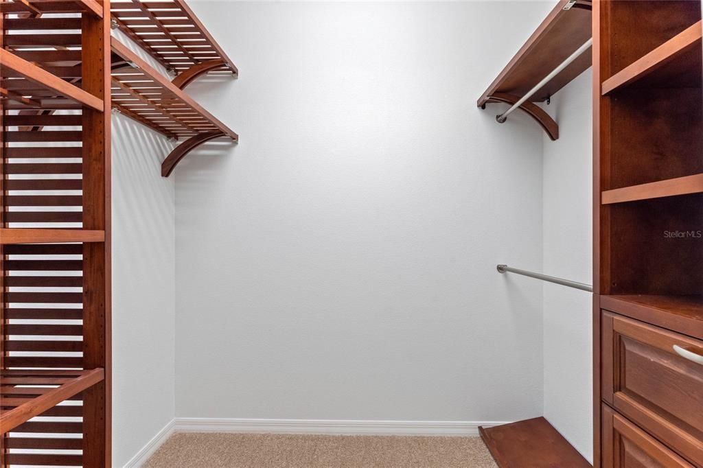 View into one of two closets in the primary bedroom that feature a closet organizer system.