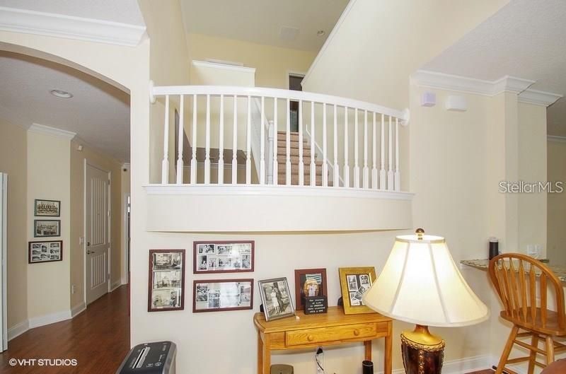 Dramatic, open stairway, with wood flooring; kitchen breakfast bar at right.