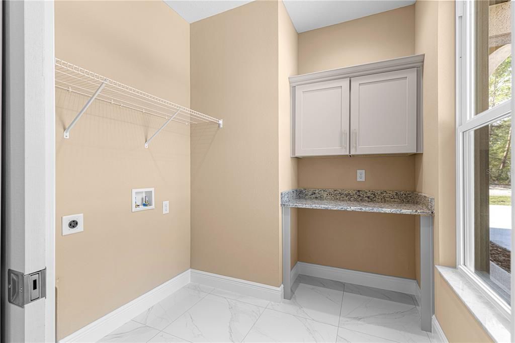 LAUNDRY WITH FOLDING BAR AND CABINET SPACCE FOR STORAGE. LAUNDRY ROOM HAS A LARGE WINDO LOOKING OUT TO FRONT YARD