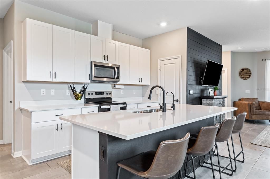 The kitchen has shaker cabinetry, quartz countertops, stainless steel appliances and island seating for 4.