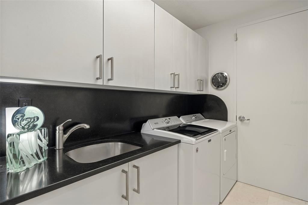 The laundry room has been revamped with a Maytag commercial washer and dryer, utility sink, cabinets, and marble countertop.