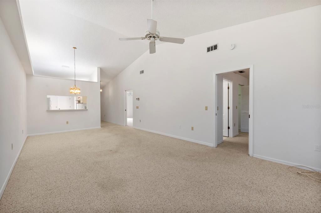 View of Great room toward kitchen and front entry. Primary bedroom off to the right.