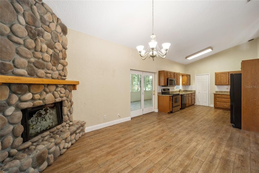 Kitchen features a stone fireplace, wood cabinets, stainless appliances and entrance to very spacious porch with view of the pond.