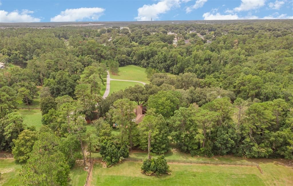 Aerial shot from above the rear pastures looking south out over the house (partially obscured by the trees)and to the front of the property