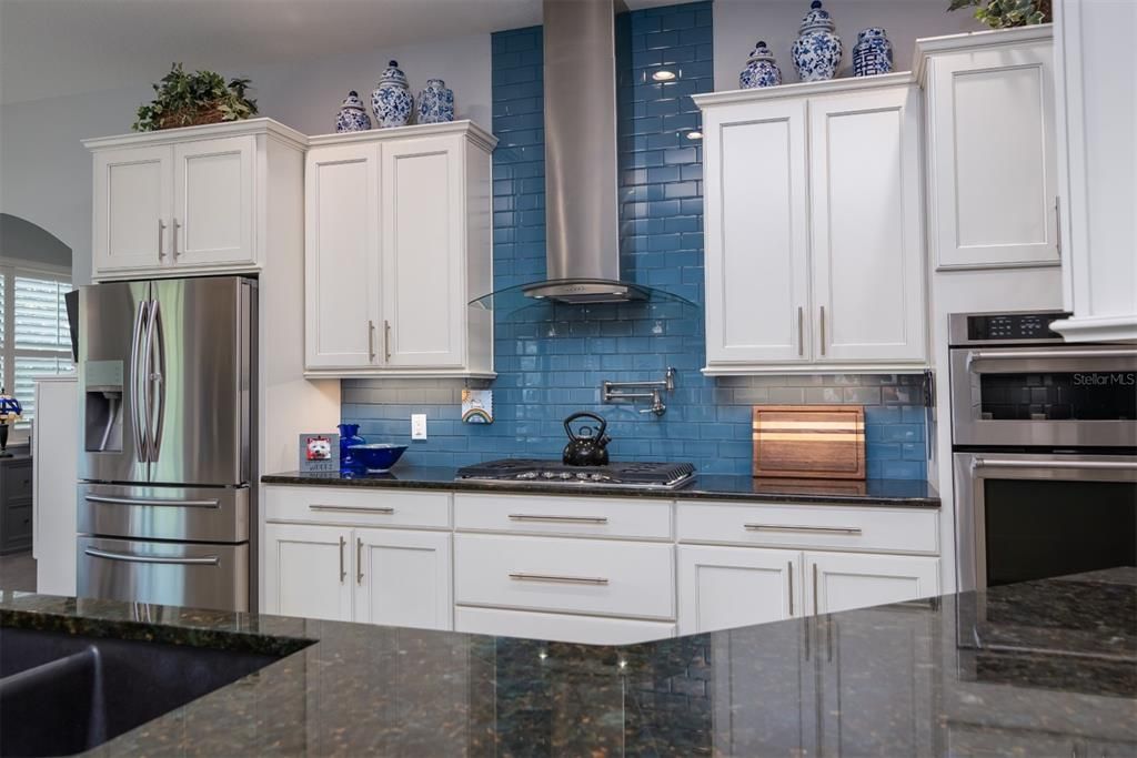 The cabinetry includes 42" uppers with crown, custom pulls, soft close doors and drawers, bank of draws, pull out shelves, and glass tile backsplash.