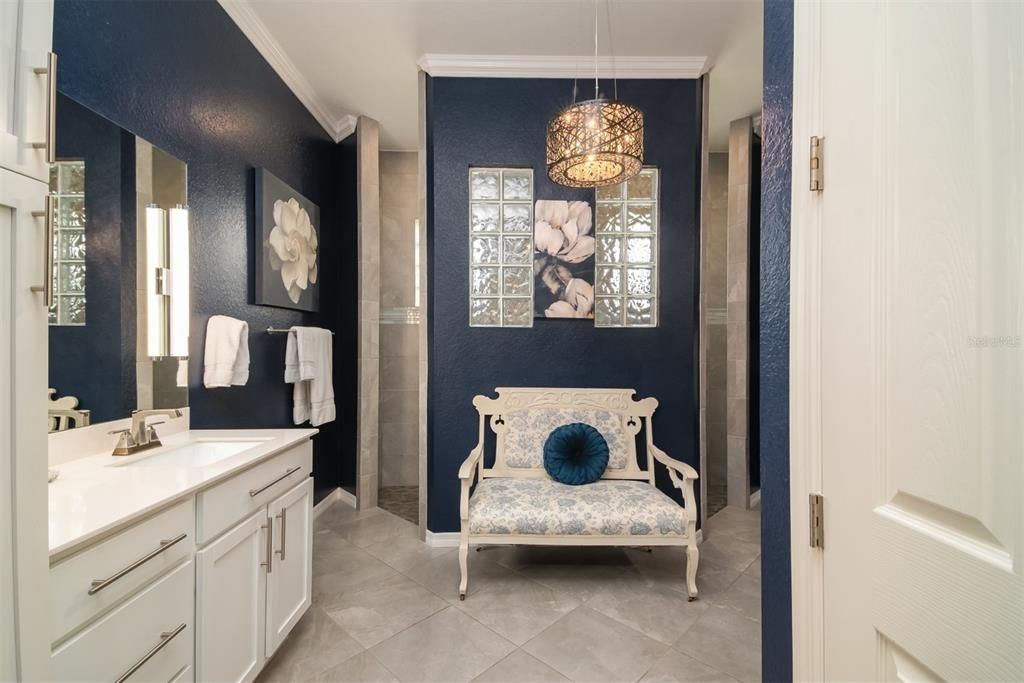 The primary bath has split vanities and a walk-thru shower. The glass blocks allow for light while maintaining privacy. The crown molding adds to this area's beauty.