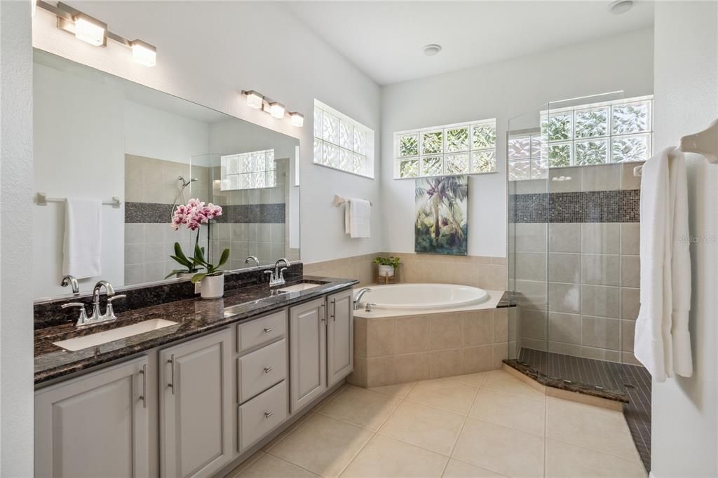 Updated Primary Ensuite bathroom with granite countertops, a frameless walk-in shower, and a relaxing soaking garden tub.