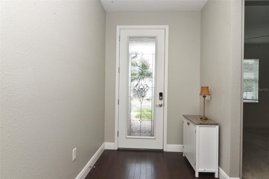 Entry foyer with 8-ft decorative glass front door, wood plank flooring