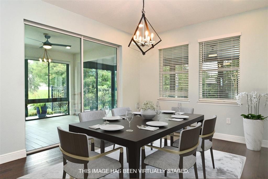 Dining room with wood floors and decorative chandelier, overlooking sunroom and fenced garden area