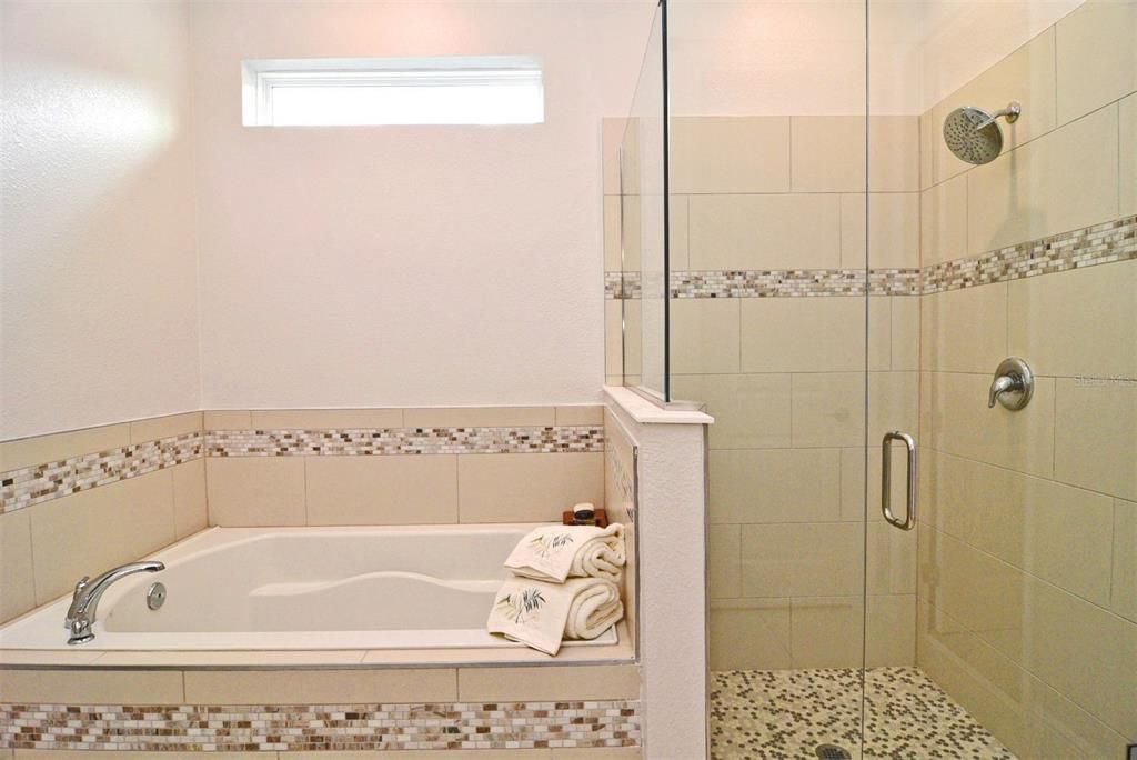 Primary Bathroom: garden tub; separate semi-frameless glass enclosed shower; large format porcelain tile floors; water closet