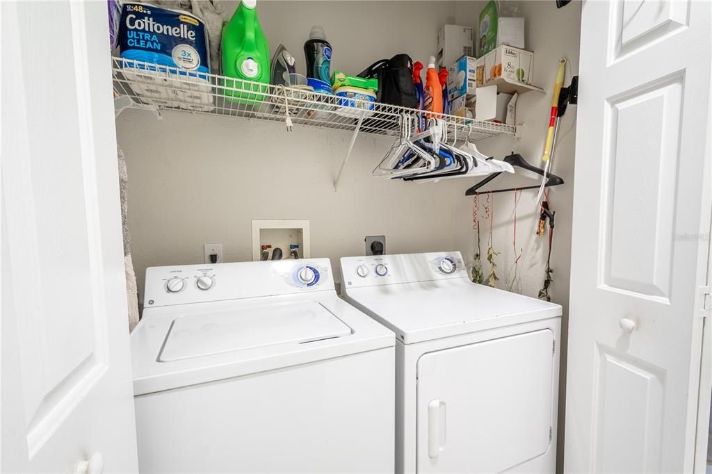 The in unit laundry closet features a washer/dryer with shelving above.