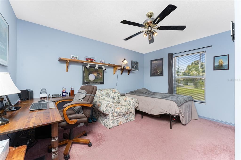 Guest bedroom #2 has carpeted flooring and a ceiling fan.