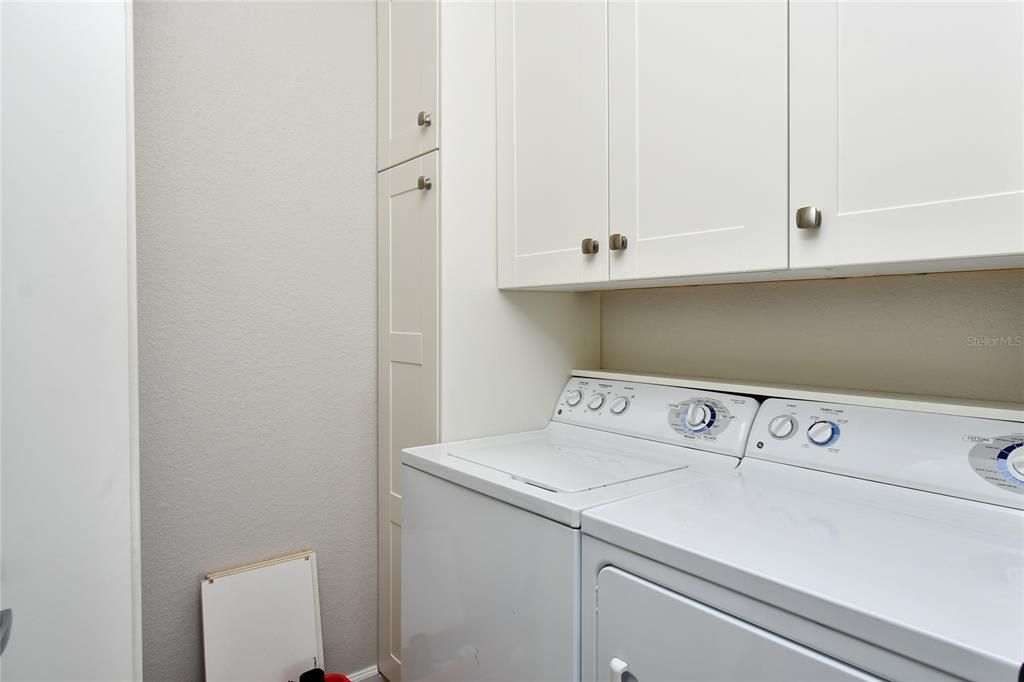 The laundry room features newer washer and dryer plus custom storage cabinets.