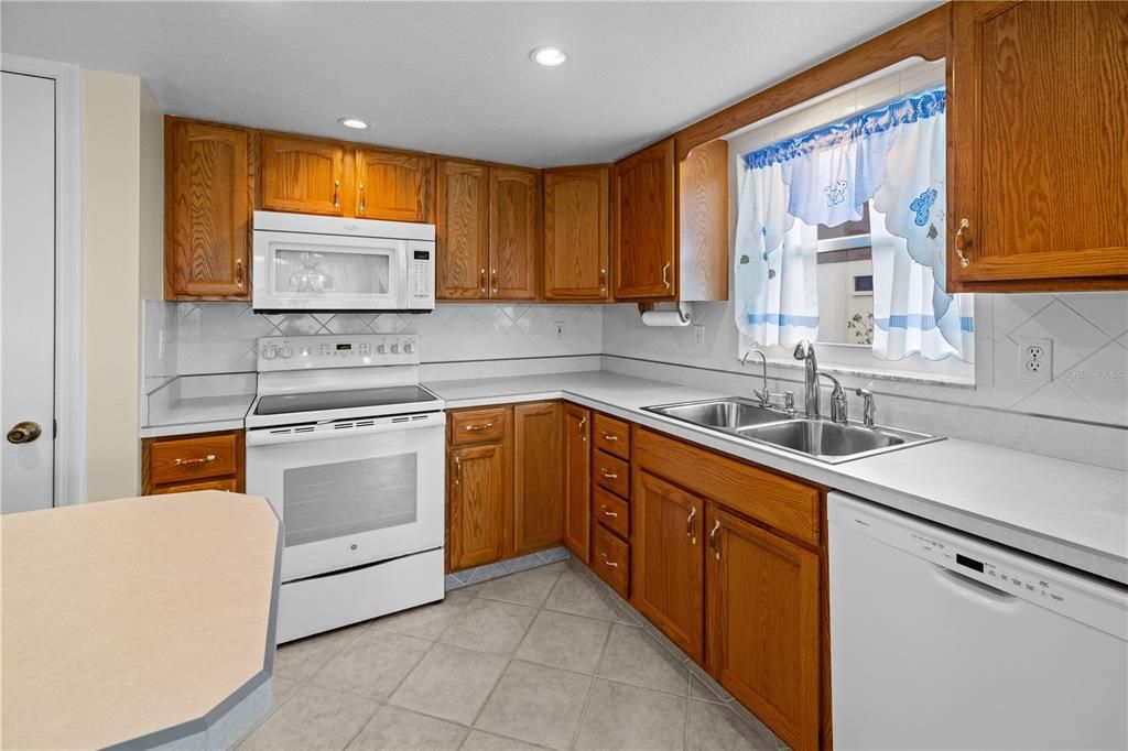 THE KITCHEN BOASTS A LARGE MOVEABLE ISLAND, OAK CABINETRY, TILE FLOORING AND A CONVENIENT PANTRY FOR EXTRA STORAGE.