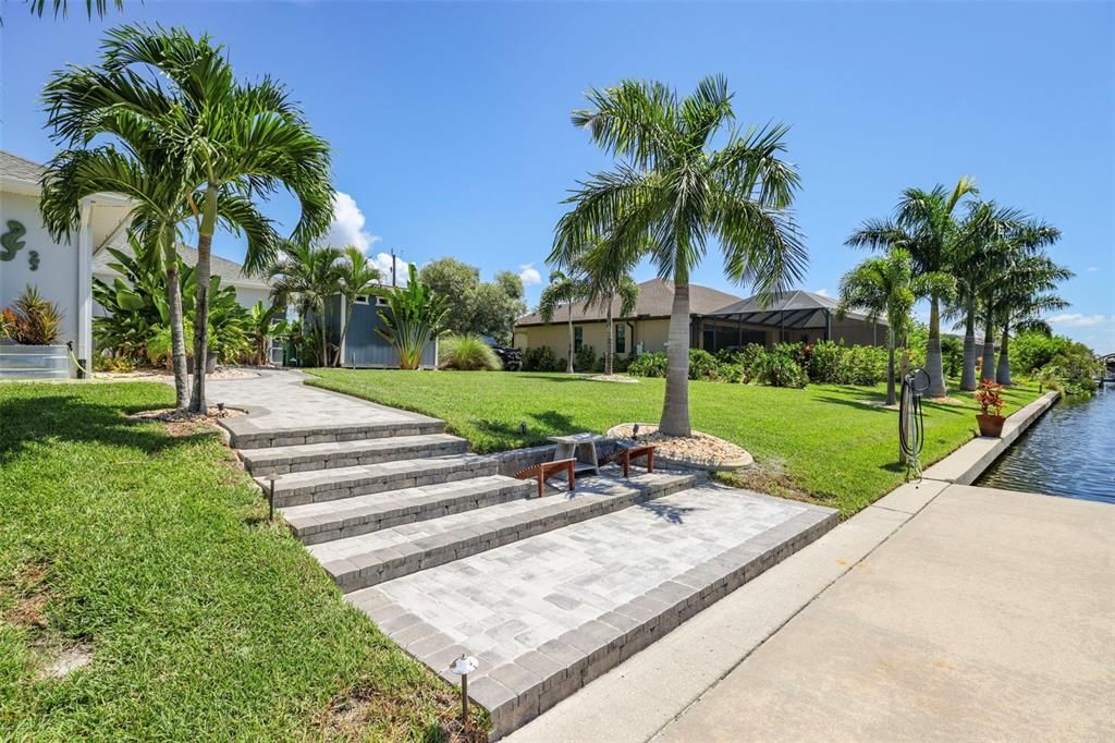 Wide pathway features new pavers, lighting and palm trees.